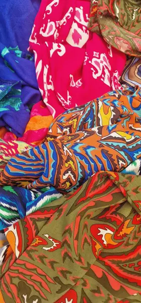 Katlanmış kumaş ve eşarplardan oluşan renkli ve kaotik bir yakın çekim. Tekstil koleksiyonunda desenler, desenler, çiçek desenleri ve zebra ve leopar gibi canlı bir kolaj oluşturan hayvan izleri yer alıyor..