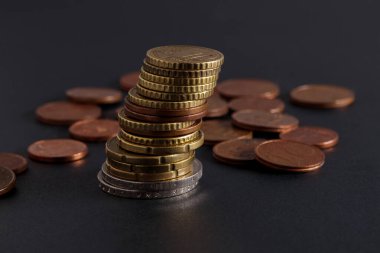 Avro paraları yığını. Farklı değerlere sahip Avrupa sikkeleri siyah bir arkaplan üzerine istiflenmiştir. Bozuk paralar birbirinin üstüne yığılmış. Tasarruf ve yatırım kavramı