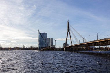 Daugava nehri boyunca Swedbank 'in ana binasına ve Riga' daki kablolu köprüye bakın. Riga, Letonya - 30 Ekim 2022.