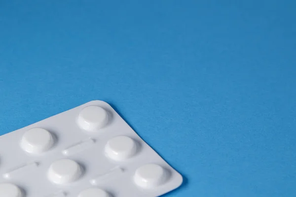 Blue background with a package of medical pills on the edge of the image. Blue medical background with free space for text, copy space