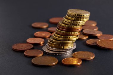 Tilted stack of coins close-up on a blurred dark background.