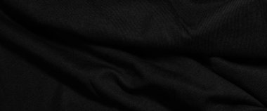 Dark wavy background made of black fabric texture. Wide panoramic black background with space for design. Web banner, website header.