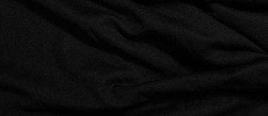 Dark wavy background made of black fabric texture. Wide panoramic black background with space for design. Web banner, website header.