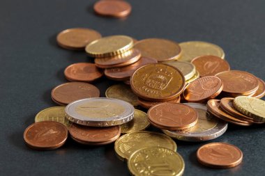 Coins on a black table. Close-up of euro coins, euro cent with the coat of arms of Latvia. Soft focus.