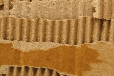 Background from torn corrugated cardboard. Brown background of torn cardboard texture with wavy pattern.