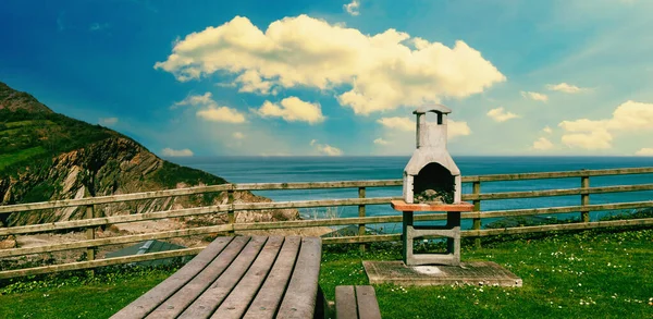 Picnic table and bbq grill in the mountains by the ocean. The concept of recreation near nature and camping.