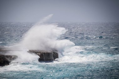 Okyanustaki büyük dalgalar büyük su sıçramalarıyla kayalara çarptı. Fırtına sırasında dramatik deniz manzarası.