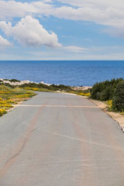 Dağlarda engebeli bir yol, arka plan mavi gökyüzü ve deniz bulanık. Yumuşak odak