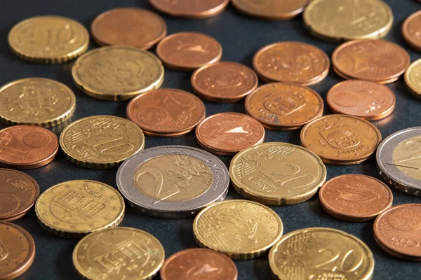 Euro sikkeleri siyah masaya yakın plan. Avro ve avro sentleri. Siyah arkaplana saçılmış farklı Avrupa paraları.