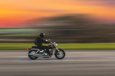 Driving motorcycle with speed blurred background. A speeding motorcycle on an asphalt street. Motion blur. clipart