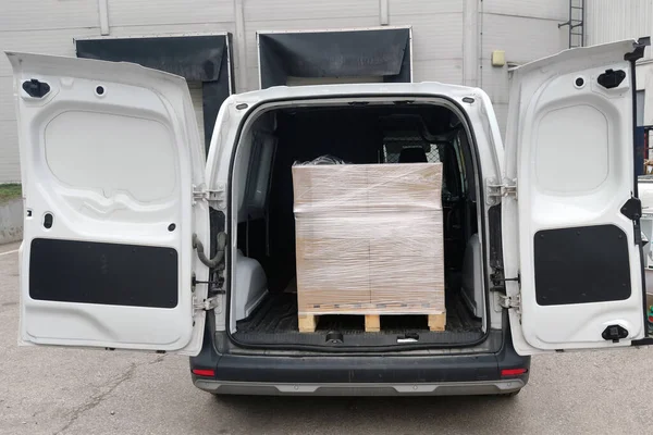 A small cargo van with cargo on a pallet in the car.
