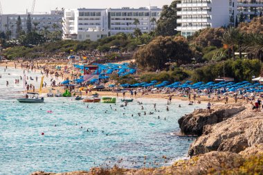 Turkuaz suyu ve tatilcileri olan Sandy Akdeniz plajı. Glyki Nero ve Pantachou Plajı, Ayia Napa, Kıbrıs - 20 Ekim 2023.