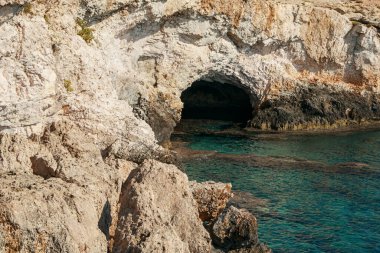 A cave in the sea. A large cave in a rock by the sea.