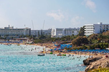 Temiz mavi suyu olan bir sahil. Plaj güneşlikleri, şemsiyeler, güneş şemsiyeleri. Kıbrıs 'ta deniz kenarında dinlenmek. Ayia Napa, Kıbrıs - 20 Ekim 2023.