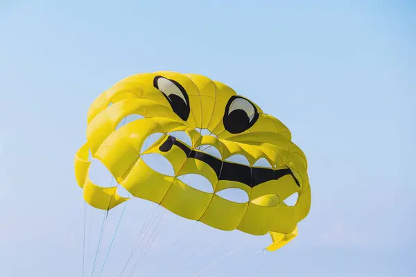 Yellow parachute with smiley face on sky background. Flying parachute with a smiley face.