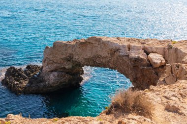 Aşıklar Köprüsü. Kıbrıs Rum Kesimi 'nin Ayia Napa kentinde doğal yollardan oluşmuş bir kaya köprüsü. Arka planda turkuaz Akdeniz ile Aşk Köprüsü.