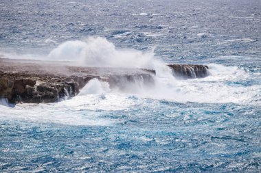 Denizde büyük dalgalar. Fırtına sırasında büyük dalgaların kayalara çarptığı deniz manzarası..