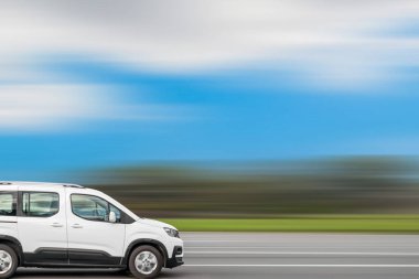 Beyaz minibüs caddede ilerliyor, hız arkaplanı bulanık ve metin için boş alan var, kopyalama alanı. Küçük kargo ve küçük paketleri kuryeyle çabucak teslim etmek..