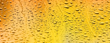 Sarı altın rengi su damlaları. Yağmurda renkli camlardan gelen bayrak.