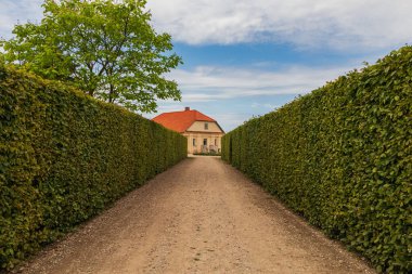 Turuncu kil kil kiremit çatılı eski bir ev. Yeşil çitli garaj yolu.