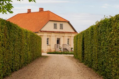 Kil kiremit çatılı, bakımlı eski bir ev. Çakıl yolu ve yeşil çitli kır evi.