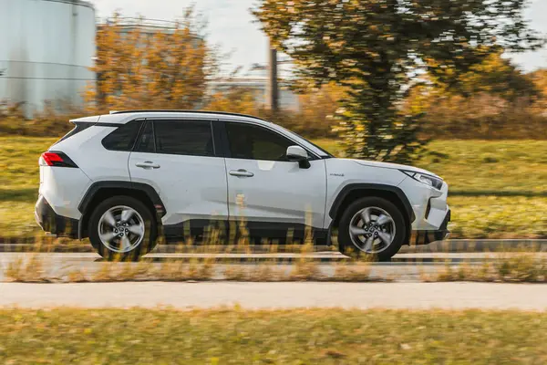 Toyota rav4 Hibrit. Asfalt bir sokakta beyaz bir araba sürüyor. Riga, Letonya - 22 Sep 2024.