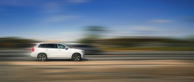 Otobandaki beyaz araba. Araba konsepti, hız, tehlikeli sürüş. Bulanık arka planda beyaz bir SUV yüksek hızda caddede ilerliyor..