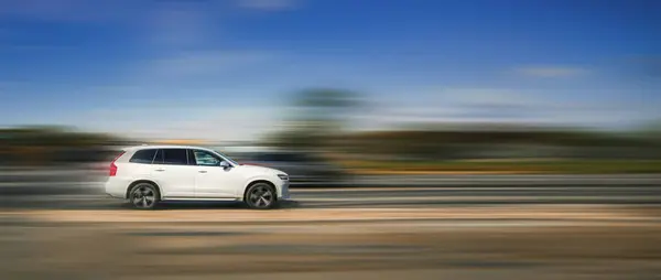 Otobandaki beyaz araba. Araba konsepti, hız, tehlikeli sürüş. Bulanık arka planda beyaz bir SUV yüksek hızda caddede ilerliyor..
