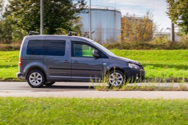 Koyu gri bir minivan güneşli bir günde yolda gidiyor. Kargo kamyonu. Küçük kargo taşımacılığı, kurye. Hızlı teslimat..