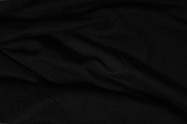 Karanlıktaki siyah kumaş. Dalgalı siyah kumaş dokusunun koyu arkaplanı.