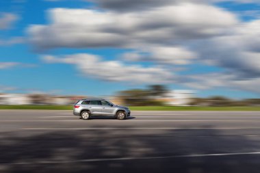 Dinamik çalışan araba yolda. Bulanık arka planı olan gri bir SUV sürücüsü.