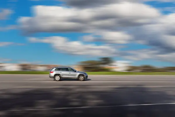 Dinamik çalışan araba yolda. Bulanık arka planı olan gri bir SUV sürücüsü.