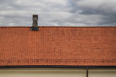 Çamur kiremit. Güzel turuncu bir çatı manzarası, arka planda bulutlu bir gökyüzü..