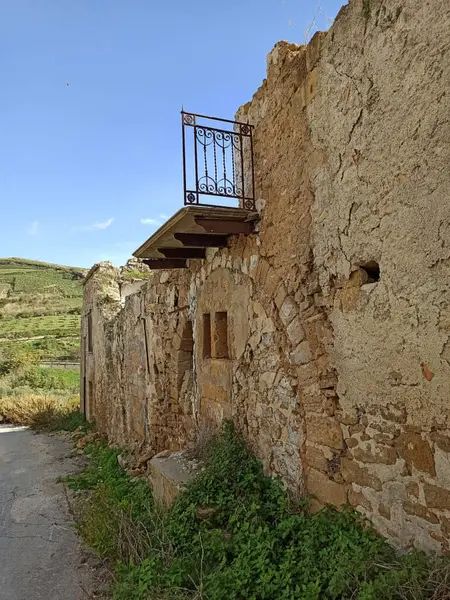 Poggioreale, Sicilya 'da terk edilmiş bir yapıda kırsal mimari, aşırı gelişmiş bitkiler ve manzaraya bakan bir balkon ve tarihi kalıntılar yer alıyor.