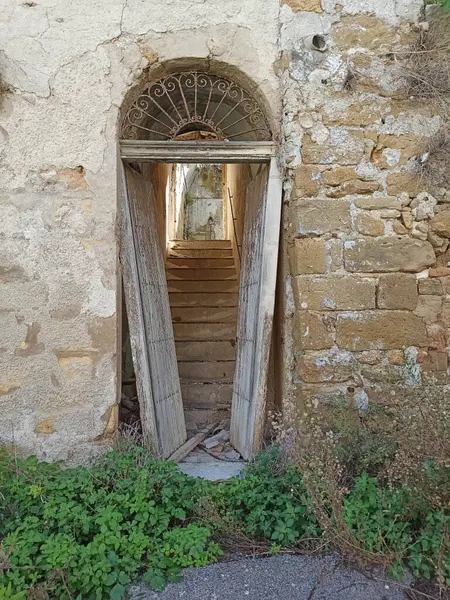 Terk edilmiş bir kapı Poggioreale, Sicilya 'da bir merdivene açılıyor, kırsal mimariyi ve tarihi cazibeyi vurguluyor, merakı ve keşfi davet ediyor.