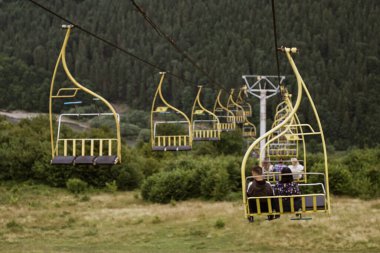 Turistleri yeşil çayırlar ve ormanlık tepelerin üzerinde taşıyan Karpat Dağları 'ndaki sarı teleferik, Ukrayna' da yaz günü manzaralı bir yolculuk.