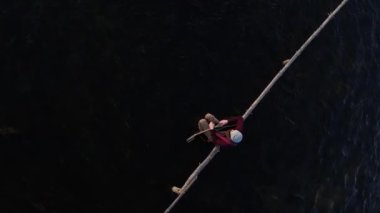 Dikey video. Su basmış bir arazinin ortasında, tahta bir kavşağın üzerindeki selde gitarlı bir adam oturuyor. Su, aletin üzerinde sergilenir. Hava tarzı dramatik bir karakter..