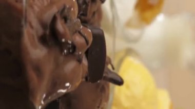 Dikey video. Dondurma, çikolata, mango ve muz aromalı üç cam kase kameranın önünde dönüyor. Beyaz dondurmada durur..