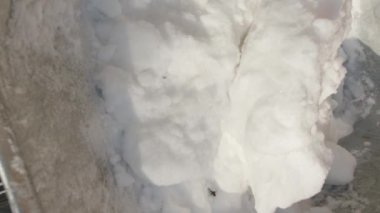 Dikey video. Metal bir kürekle metal bir el arabasına kar atmak..