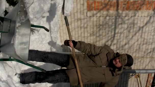 Vídeo Vertical Homem Joga Uma Neve Carrinho Mão Metal Sob — Vídeo de Stock