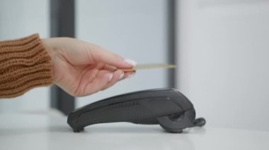 Beyaz bir arka planda cilalanmış manikürlü bir kadının eli NFC teknolojisi kullanarak ulaşılamaz bir kredi kartıyla ödeme yapıyor. Kablosuz para transferleri. Kablosuz ödeme.