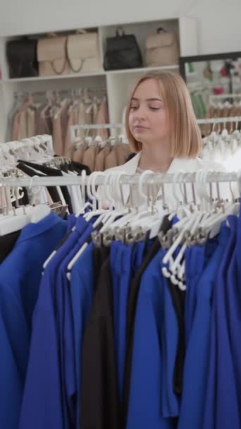 Ung Blond Kvinna Vita Företagskläder Väljer Outfit Hylla Butik Han — Stockvideo