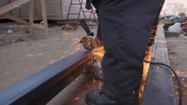 An employee cuts a metal profile with an angle grinder. Shooting on the street, Slow motion shooting. Sparks fly.
