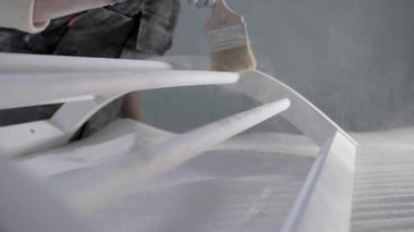 Dişi bir marangoz, ahşap bir mobilyayı parlattıktan sonra tozu fırçayla süpürür..
