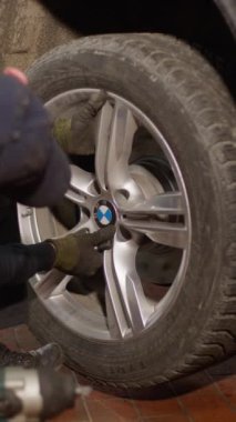 Lutsk, Ukraine - February 17, 2023: a mechanic changes a tire of a BMW X5 / The mechanic puts the car wheel on the hub and tightens the bolts.