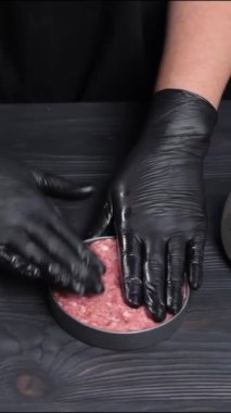 Dikey video. Pişirmek için hamburger malzemesi oluşturuyorum. Şef hamburger pişirmeden önce köfteyi şekillendirmek için sığır eti eziyor. Mutfakta lezzetli fast food biftekli hamburger pişirmek. Amerikalı.