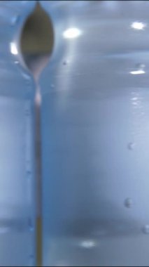 Vertical video. Close up of a plastic bottle filled with carbonated mineral water. Floating bubbles. Conveyor line of the food industry.