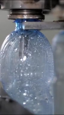 Dikey video. Dolum ünitesinde 0.5 litre hacimli plastik bir şişeye su dök. Maden suyu ve meşrubat üretimi için alışveriş..