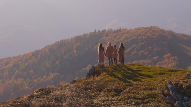 乌克兰秋天的群山覆盖着森林 一家人站在悬崖边上向前看 少男少女都是棕色外套 手牵手 空中景观 — 图库视频影像