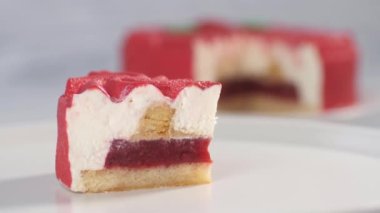 Beyaz bir tabakta kesilmiş bir çilekli kek parçası yavaşça tüm şekerlemenin arka planına doğru kayıyor. Tatlı ürünleri.